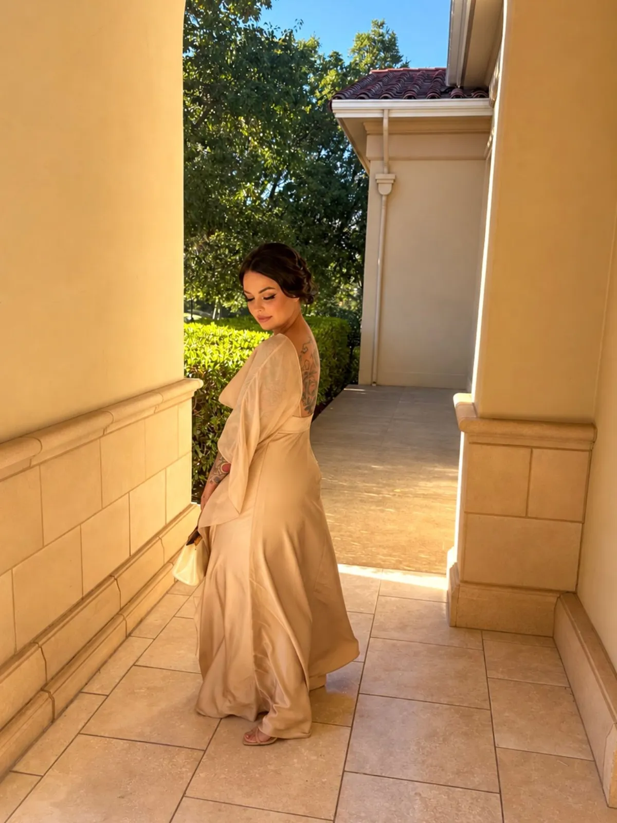 Real Glowtoure client from a wedding party in a champagne satin gown at the venue, with a warm, even glow across her back, shoulders and arms