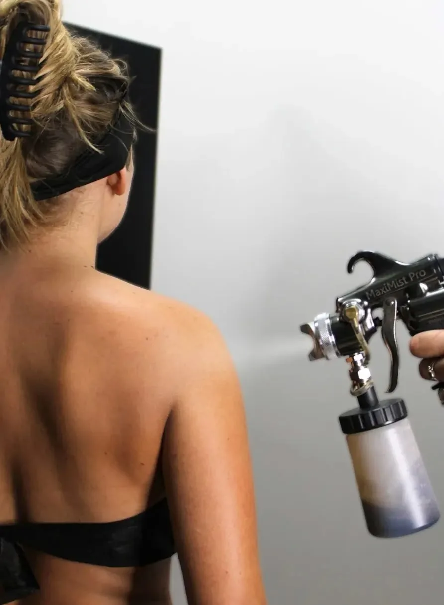 A Glowtoure mobile spray tan being applied to a client with a professional airbrush gun